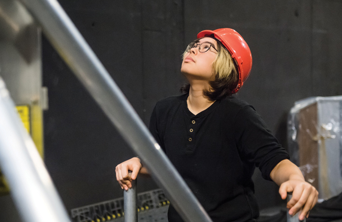 A theatre technician stabilises a ladder while observing changes to the lighting rig. Photo: Alex Brenner