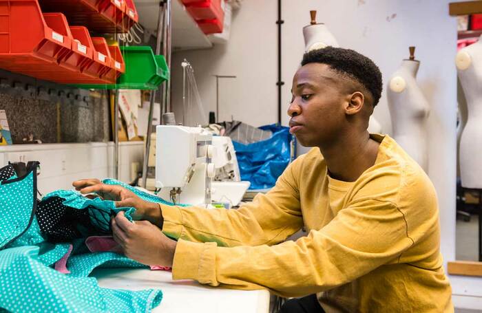 Costume designer with Tiata Fahodzi modifies a garment. Photo: Alex Brenner