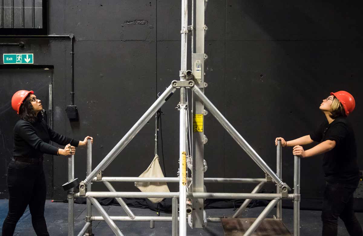 Two theatre technicians provide support for a ladder during rigging. Photo: Alex Brenner/Tiata Fahodzi